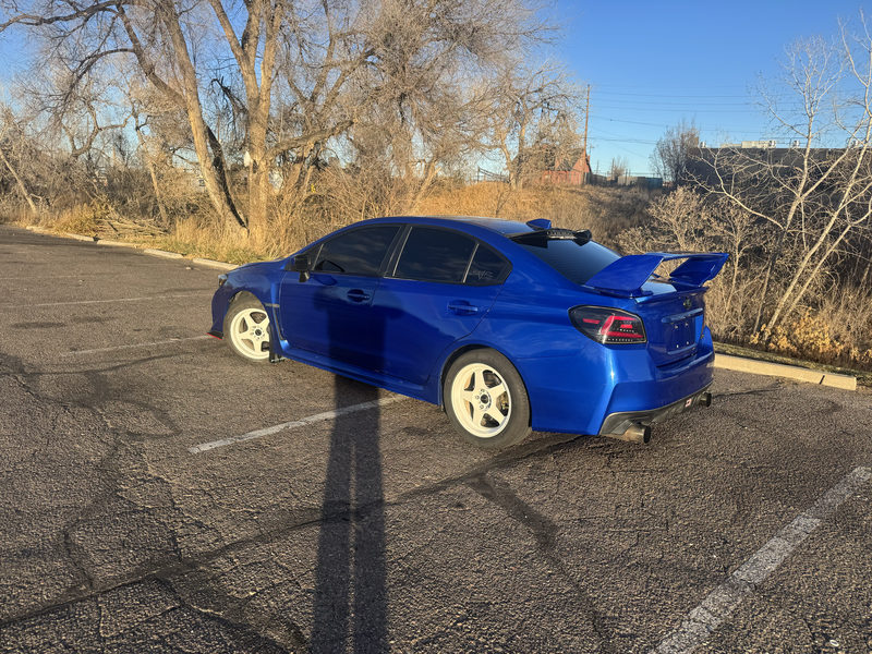 Blue Subaru WRX with a tall rear wing and white wheels