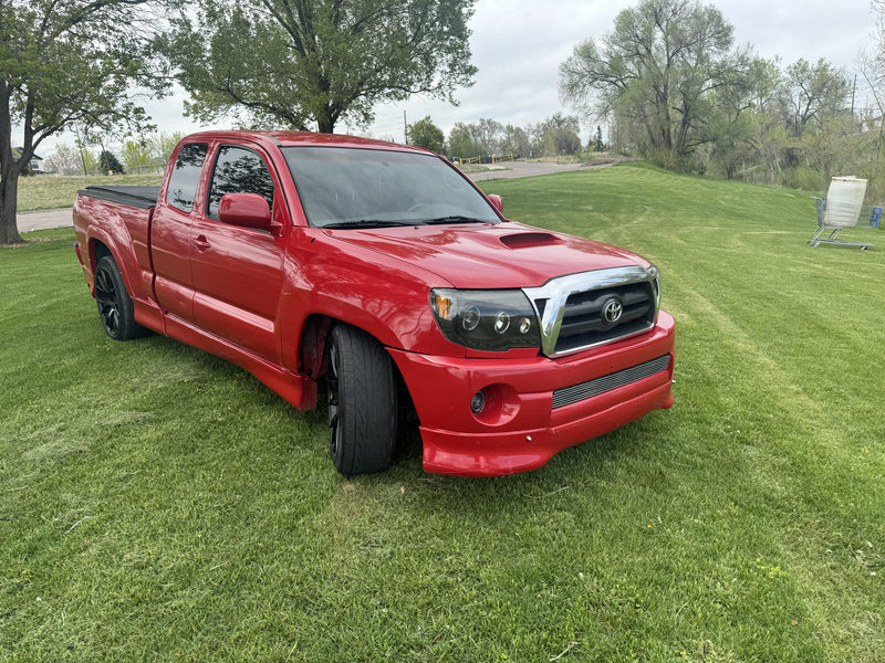 Lowered red Toyota Tacoma on black wheels