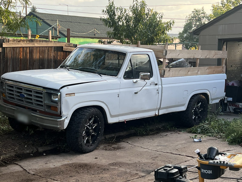 White classic Ford pickup with a wooden stake bed and black wheels