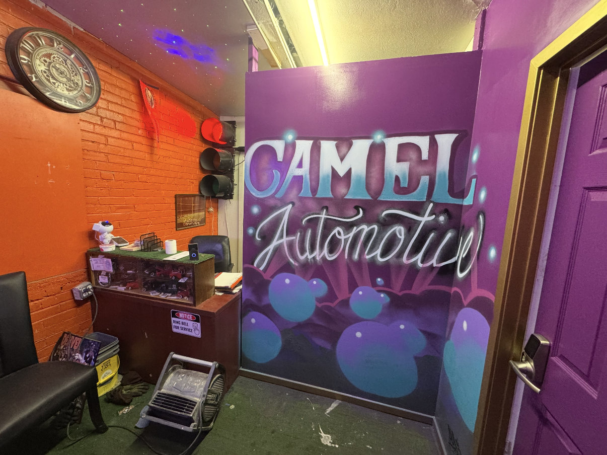 Purple Camel Automotive mural beside the reception counter, chair and traffic light.